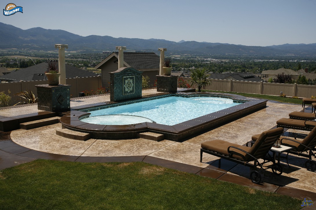 The Caesar's Palace is a elegant grecian pool shape that includes an attached spa with a set of shallow end entry steps. The Caesar's Palace is seen here with a raised pool coping and architecture that boosts this pool shapes elegance and artistic design.