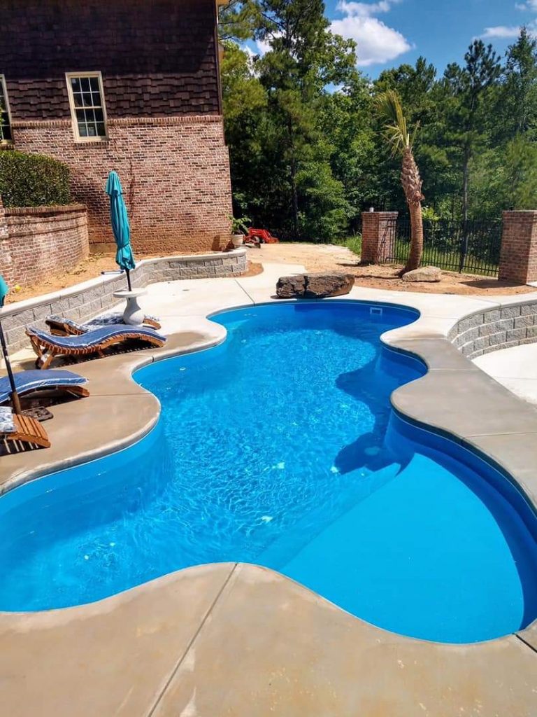 The Desert Falls is a fun and lavish fiberglass swimming pool with a wild free form pool shape. It sports a 6'  1.25" deep end and a standard hopper with a gradual slope from the shallow end. As seen in this image, the shallow end includes a wide tanning ledge (shown here with two bubblers). 